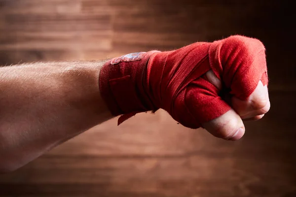 Feche a imagem do punho de um boxeador com atadura vermelha contra fundo marrom . — Fotografia de Stock
