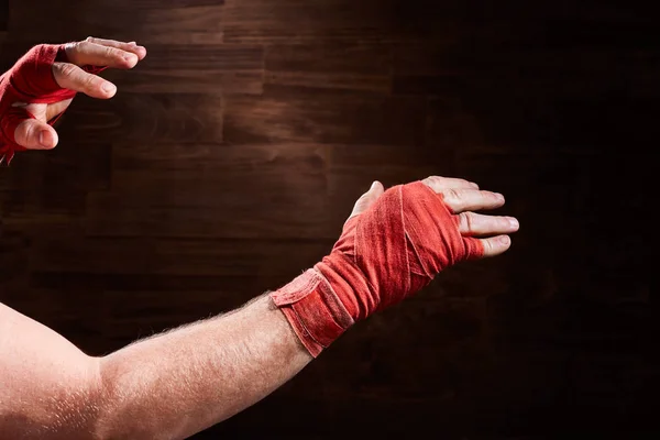 Mãos de homem atlético muscular com bandagem vermelha contra fundo marrom . — Fotografia de Stock