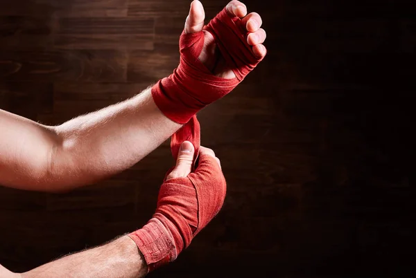 Boxeador poniendo vendaje alrededor de muñecas y manos contra pared marrón . —  Fotos de Stock