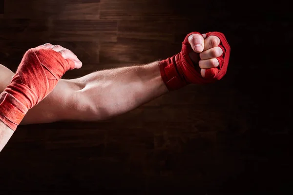 Manos de hombre atlético muscular con vendaje rojo sobre fondo marrón . —  Fotos de Stock