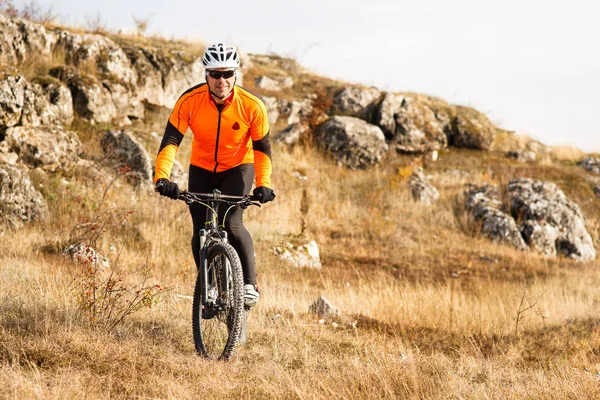Ποδηλάτης ιππασίας το ποδήλατο κάτω από βραχώδη λόφο. Extreme Sport έννοια. Χώρο για το κείμενο. — Φωτογραφία Αρχείου