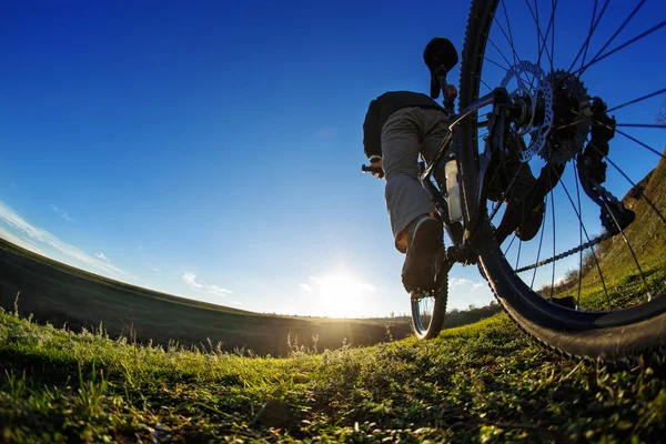 Man on mountain bike rides on the trail on a beautiful sunrise. Bicycle wheel closeup.