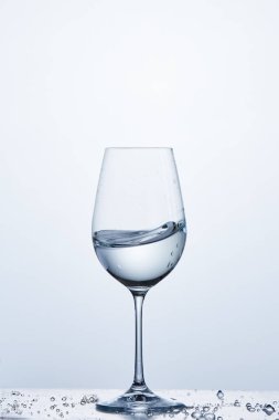 Açık renkli karşı su kabarcıkları ile cam üzerinde dururken şarap cam dalga saf su.