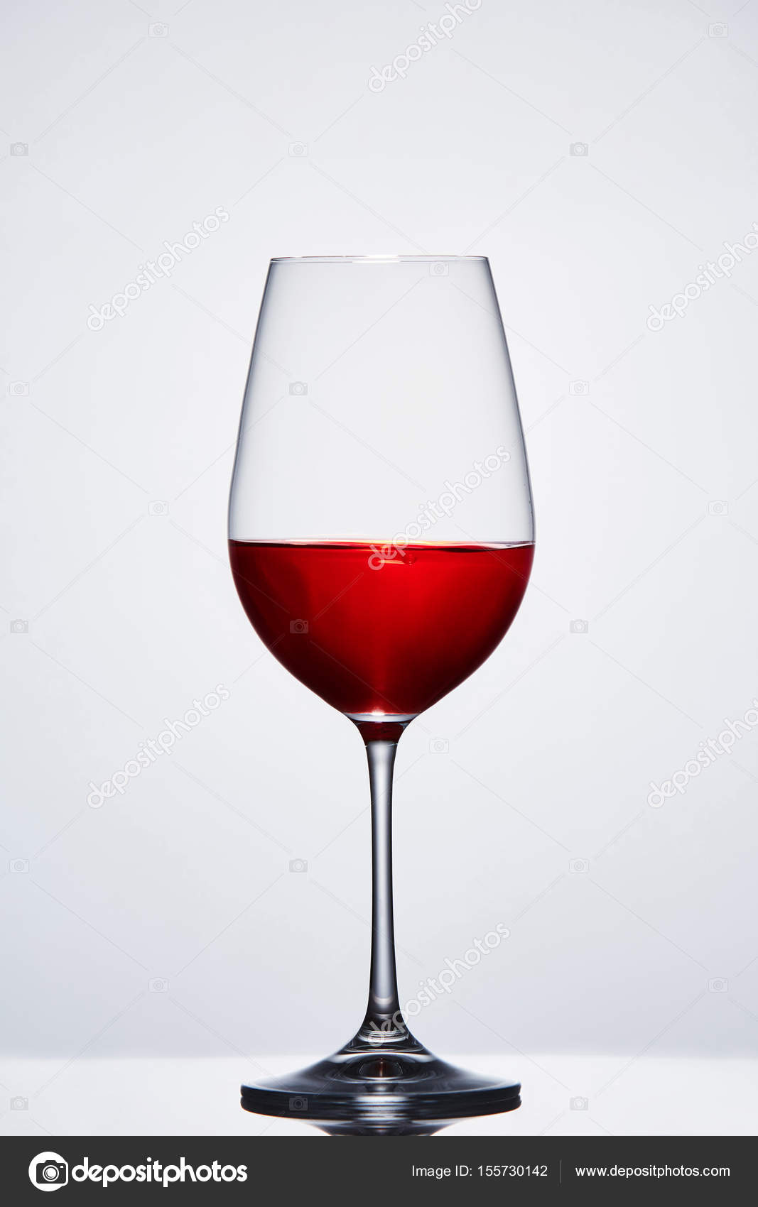 Halffull wine pure wine glass with red wine against light background