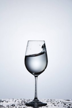 Açık renkli karşı damlacıkları ile cam üzerinde dururken şarap cam dalga şeffaf su sıçramasına.