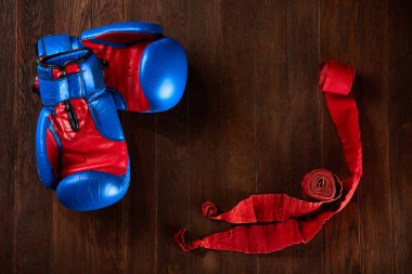 Mavi ve kırmızı eldiven ve ahşap arka plan üzerinde kırmızı bandaj ile spor arka plan.