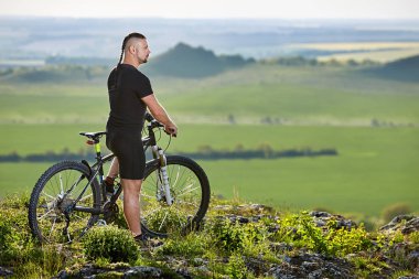 Güzel manzara arka plan üzerinde dağ bisikleti ile ayakta bisikletçi.