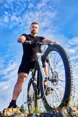 Genç bisikletçi bisiklet buzlu mavi gökyüzü ile ayakta alttan görünüm.