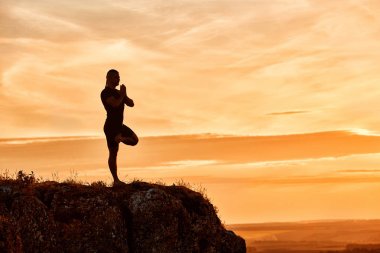 Pratik yoga güzel gün batımını karşı tepedeki adam silüeti.