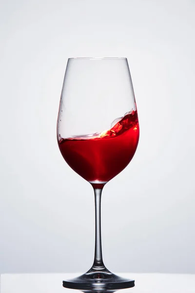 Vin rouge dans un verre à vin pur cristallin montrant des vagues sur fond de lumière . — Photo