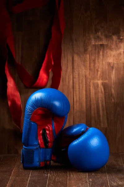 Dwa niebieskie i czerwone rękawice bokserskie i bandaż czerwonym tle drewnianych. — Zdjęcie stockowe