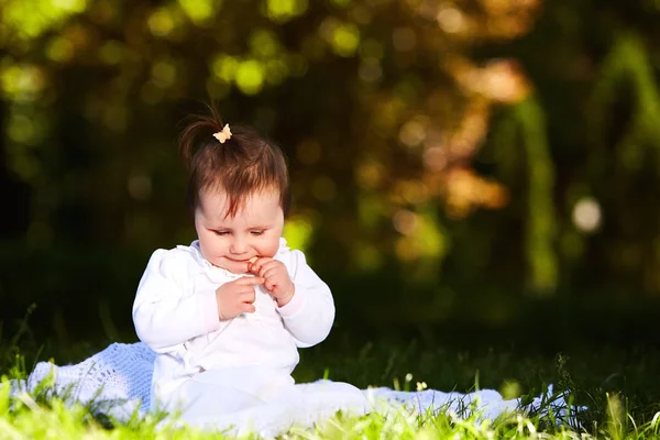 Adorable linda niña sentada en el prado verde y comiendo la pastelería . — Foto de Stock
