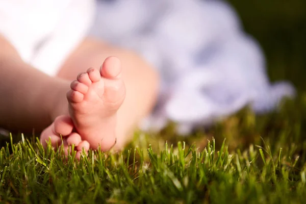 Primer plano de los pequeños pies de bebé sobre hierba verde al aire libre en el parque de la ciudad . — Foto de Stock