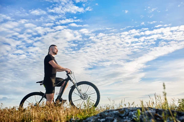 Ciclista de pé com bicicleta de montanha no fundo do céu bonito com nuvens . — Fotografia de Stock