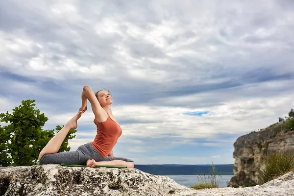 Donna sportiva praticare yoga sulla roccia contro bellissimo paesaggio . — Foto Stock