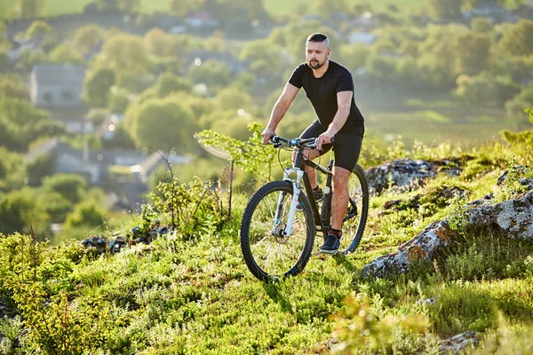 Extreme mountain cyclist riding bike on rocky trail in the countryside.