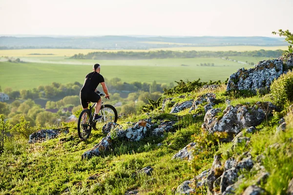 Visão traseira do jovem ciclista andando de bicicleta na trilha rochosa no verão . — Fotografia de Stock