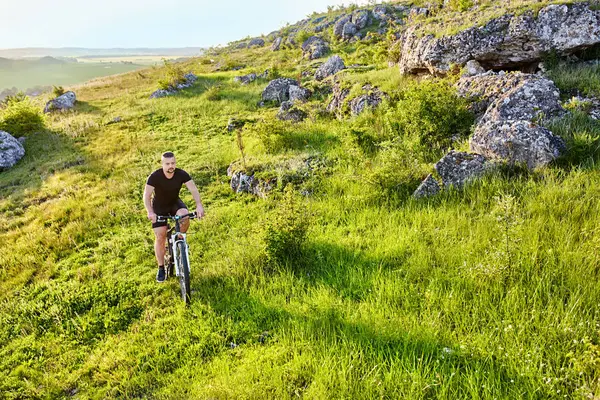 Atraktivní cyklista jízdu na letních stezka poblíž krásné velké skály. — Stock fotografie