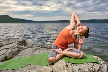 Çekici kadın güzel Nehri yakınında taş yoga uygulamak.