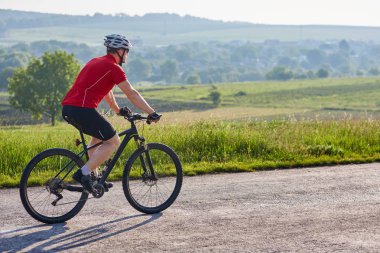 Çekici bir adam beyaz kask ülke yolda Bisiklete binmek içinde.
