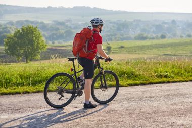 Çekici bir adam beyaz kask ülke yolda Bisiklete binmek içinde.