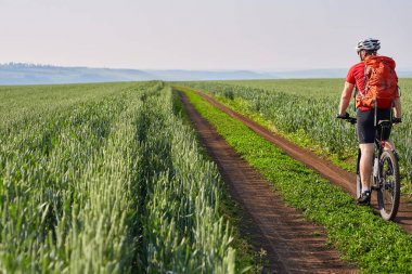 Genç bisikletçi de yol alan parlak güneşli bir günde kırsal kesimde rides.