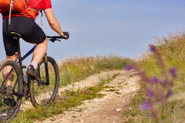 Arkadan görünüş ve kırsal yaz alanında genç bisikletçi binicilik bisiklet close-up.