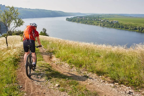 Pohled zezadu mladá atraktivní cyklista jízdní horské kolo v letní louka. — Stock fotografie