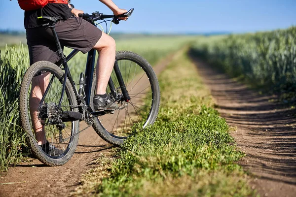 Close-up de homem ciclista pernas com bicicleta de montanha na trilha de campo no campo . — Fotografia de Stock
