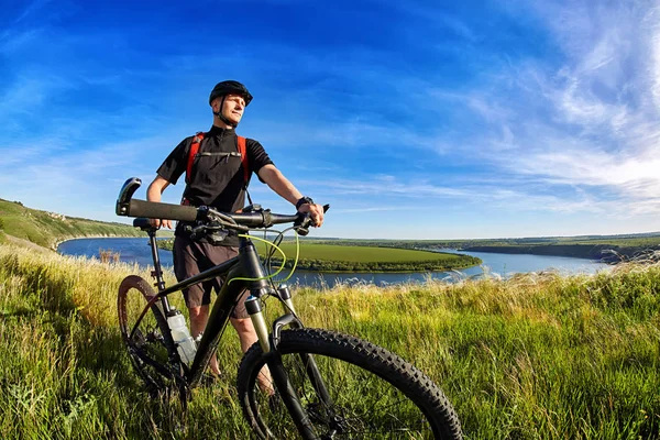 Attraktive Mountainbiker steht auf dem Hügel über dem schönen Fluss. — Stockfoto