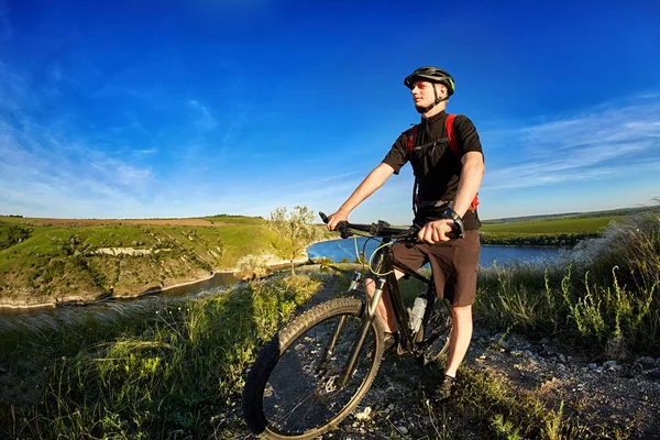 Retrato del ciclista con bicicleta de montaña sobre un fondo de cielo azul con nubes . — Foto de Stock