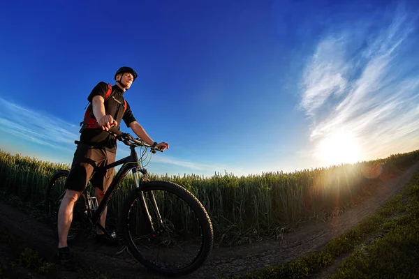 Retrato del ciclista con bicicleta de montaña sobre un fondo de cielo azul con nubes . —  Fotos de Stock