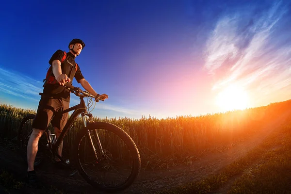 Ângulo largo do ciclista em pé na trilha no campo contra a bela paisagem . — Fotografia de Stock