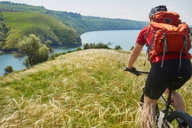 Arkadan görünüş ve kırsal yaz alanında genç bisikletçi binicilik bisiklet close-up.