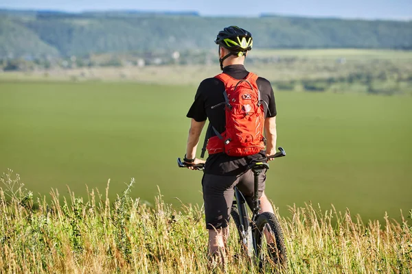Vista trasera del ciclista de pie con bicicleta de montaña contra el hermoso paisaje . — Foto de Stock
