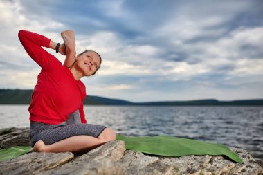 Açık havada Nehri yakınında taş üzerinde Yoga egzersiz yaparak mutlu genç kadın.