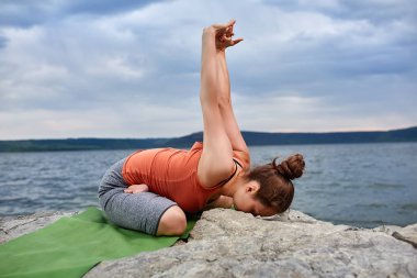 Çekici kadın yapma yoga egzersiz güzel nehir karşı büyük taş.