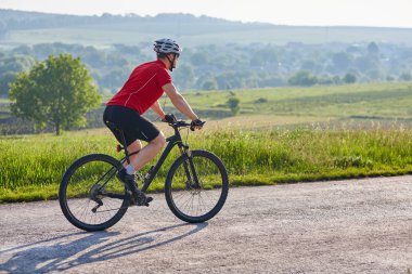 Genç çekici bisikletçi binme dağ bisikleti ülke yolda.