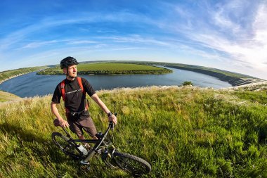 Çekici bisikletçi dağ bisikletçi güzel nehir karşı ile tepede duran.