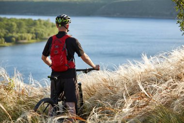 Genç bisikletçi dağ bisikleti güzel nehir karşı ayakta arkadan görünüş.