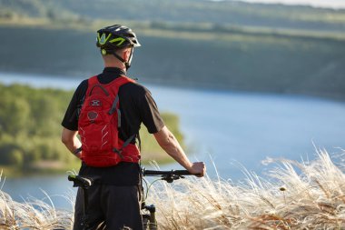 Genç bisikletçi dağ bisikleti güzel nehir karşı ayakta arkadan görünüş.