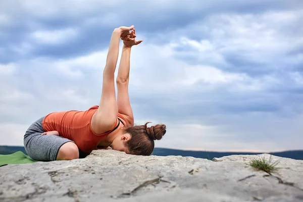 Mulher atraente fazendo exercício de ioga na grande pedra contra belo rio . — Fotografia de Stock