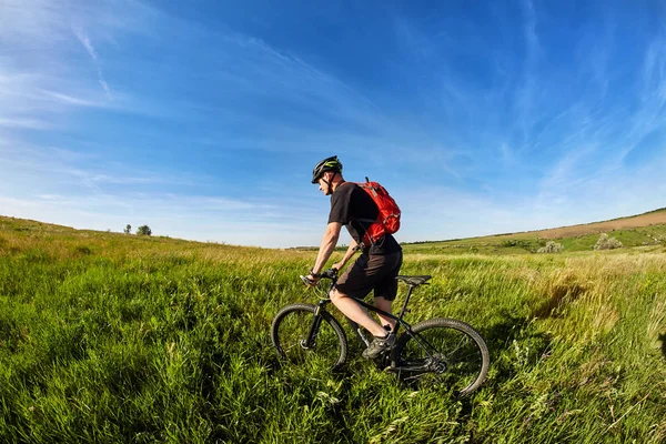 Mladý cyklista na koni horský cyklista proti krásný východ slunce na venkově. — Stock fotografie