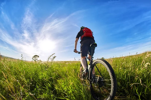 Junge Radfahrerin fährt Mountainbiker gegen schönen Sonnenaufgang auf dem Land. — Stockfoto