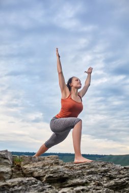 Taş üzerinde duran ve pratik yoga büyük Nehri yakınında genç kadın.
