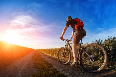 Kask binme dağ bisikletçi gündoğumu karşı açık izinde bisikletçi.