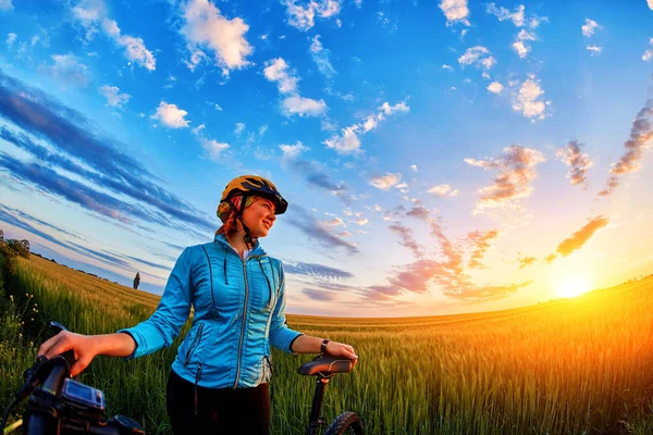 Młody Pani z rowerem na łąkę o zachodzie słońca. — Zdjęcie stockowe