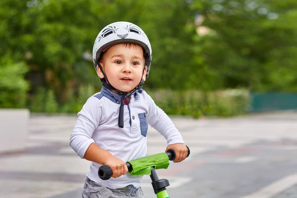 Child boy in white helmet riding on his first bike with a helmet. Bike without pedals.