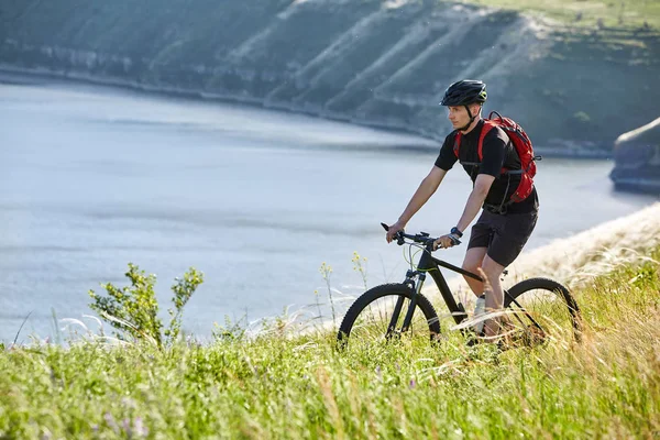 Atraktivní cyklista jízda horské kolo na letní stezky nad řekou. — Stock fotografie