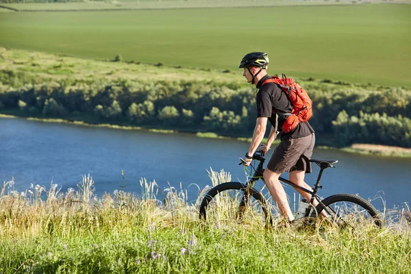 Atraktivní cyklista jízda horské kolo na letní stezky nad řekou. — Stock fotografie